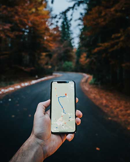 Ein Smartphone mit Routenplaner vor einer verlassenen Straße im Wald