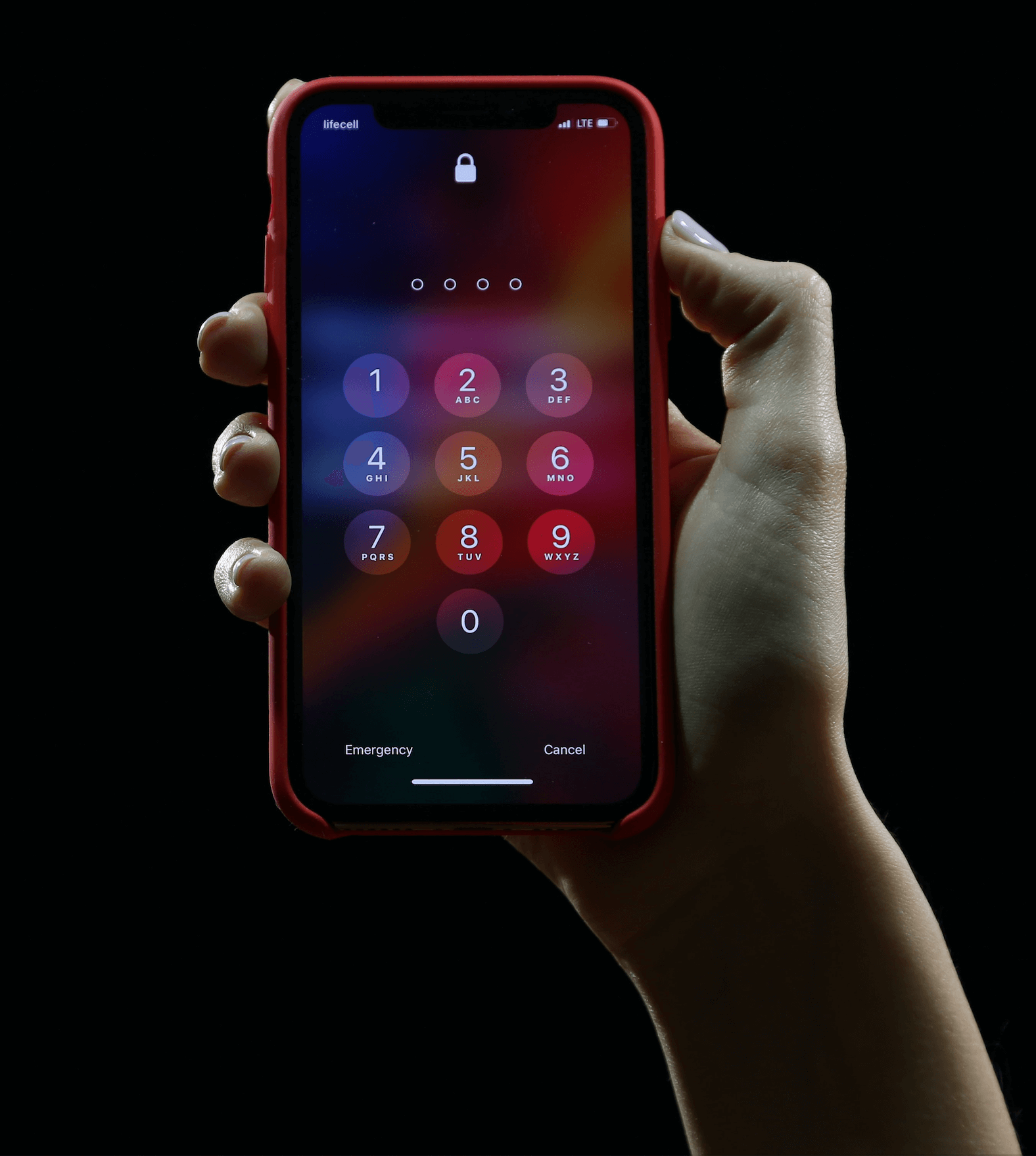 Eine Hand hält ein iPhone vor schwarzem Hintergrund. Der Bildschirm des Smartphones ist versperrt und der Dialog zur Eingabe der PIN ist sichtbar.