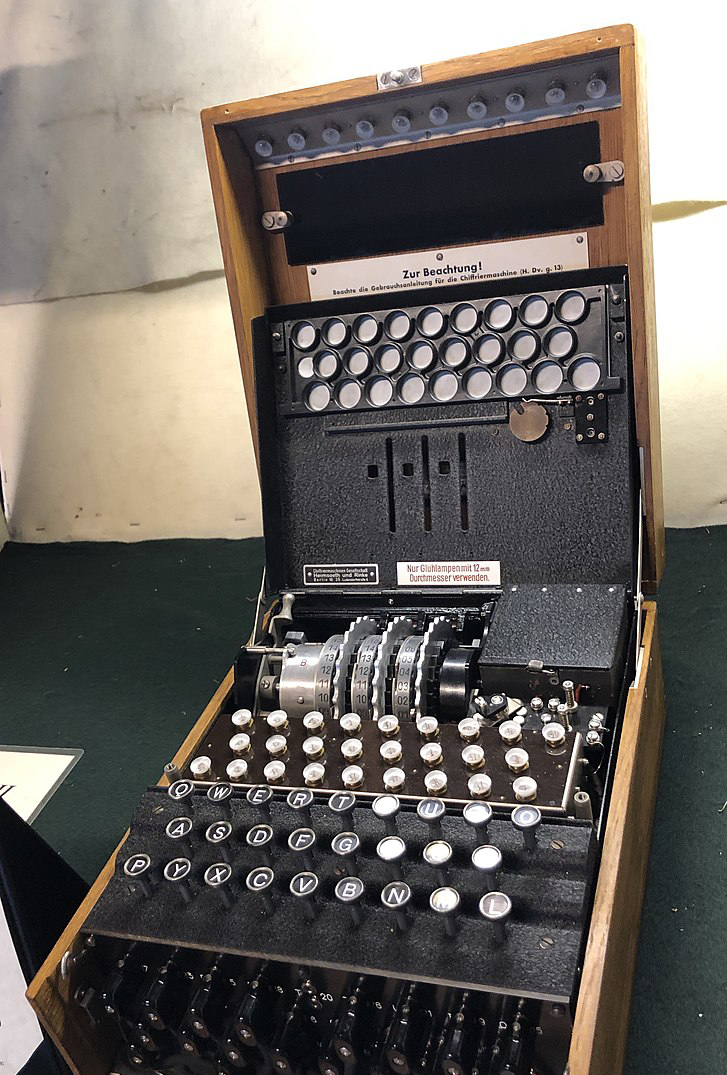 Foto einer aufgeklappten Enigma Verschlüsselungsmaschine. Sichtbar sind unterschiedliche Räder und Tasten.