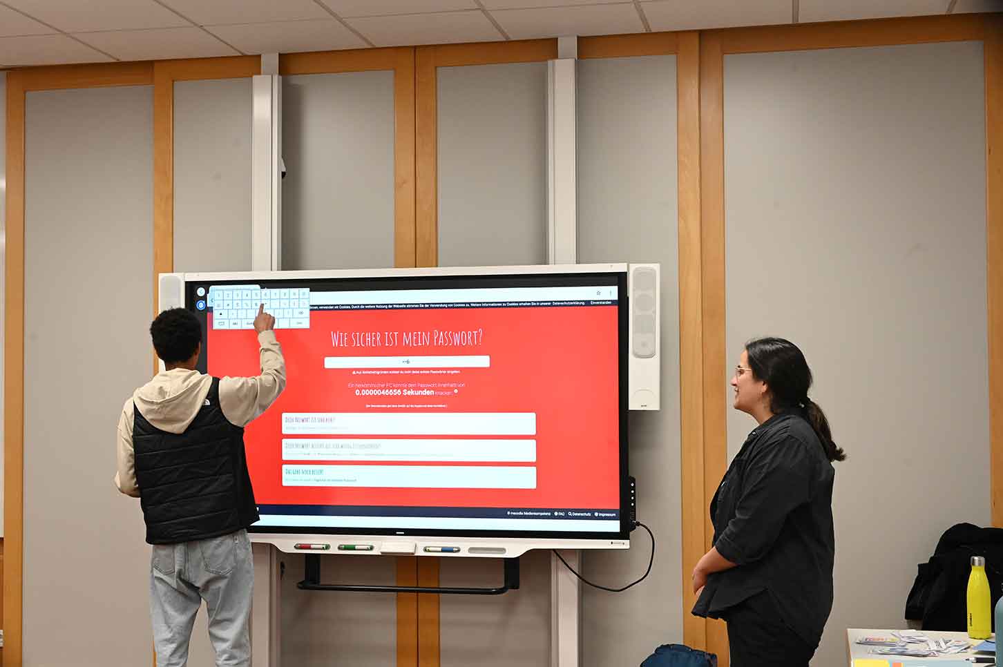 Ein Schüler prüft ein erstelltes Passwortmit Hilfe einer Webseite am Smartboard